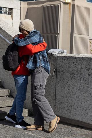 Teenage couple embracing on urban campus steps in warm sunlight
