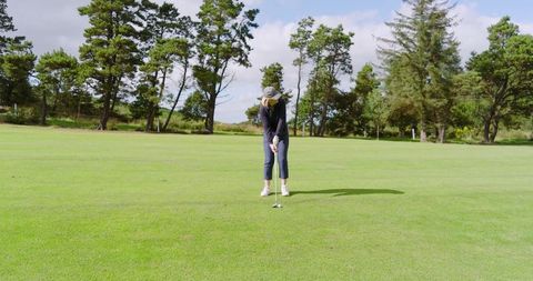 Female Golfer Preparing to Putt on Sunny Green Course