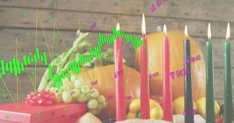 Celebrating kwanzaa with glowing kinara and harvest still life overlaid with stock market graph