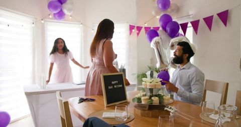 Family arranging birthday decorations with cupcakes at home celebration