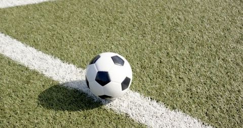 Soccer ball on white line in sunlit athletic field