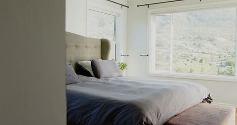 King-size bed creating minimalist neutral bedroom with tufted headboard and mountain view