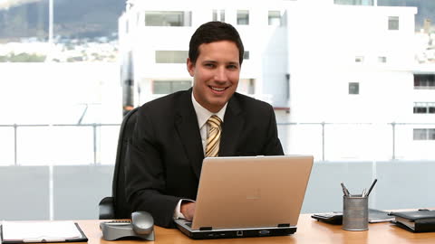 Smiling Businessman Working on Laptop in Office