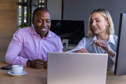 Diverse Professionals Collaborating on Laptop in Modern Office Setting