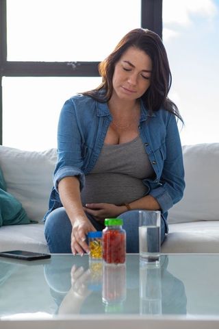 Pregnant woman at home with supplements, promoting maternal health