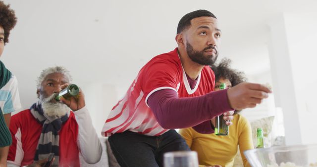 Group of friends intensely watching a sports game on TV while enjoying beer together. They appear focused and excited about the event. Ideal for use in content relating to sports, fan culture, gatherings, and entertainment.