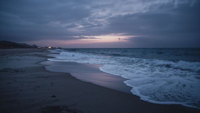 Twilight Beach Reflecting Pastel Sky, Waves Rolling onto Quiet Shoreline at Dusk