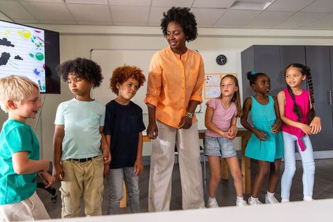 African American teacher leading diverse elementary students in classroom activity