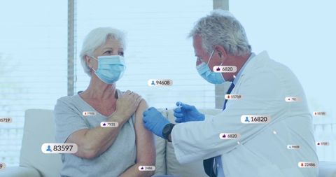 Senior woman receiving covid-19 vaccine from masked doctor with floating engagement badges