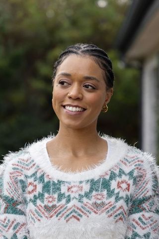 African american woman smiling wearing fuzzy patterned sweater and gold hoop earrings
