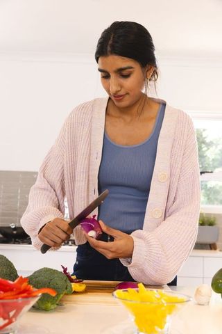 Woman Slicing Red Onion in Modern Home Kitchen