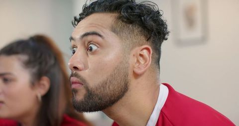 Intense match-watching closeup young friends leaning forward in red jersey focused gaze