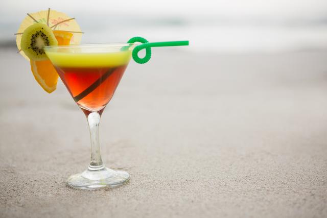 Glass of cocktail drink kept on sand at tropical beach