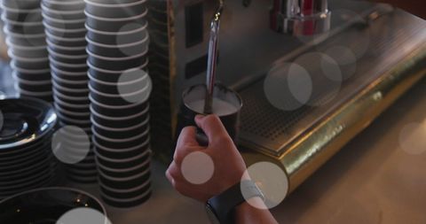 Barista steam milk for latte art creation in cozy cafe atmosphere