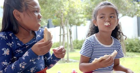 Two Young Girls Enjoying Lunch Outdoors Together