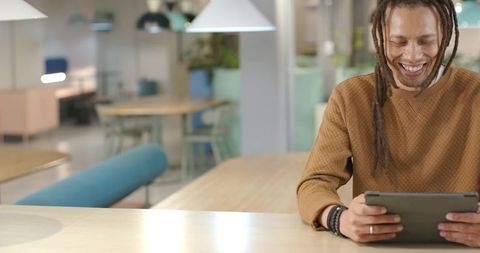 African American Man Smiling While Holding Tablet in Modern Coworking Space