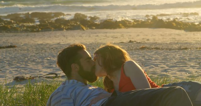Beautiful romantic couple lying down and kissing on the beach. Couple romancing on beach during sunset 4k