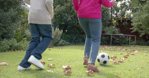 Mother and Son Enjoying Soccer Game in Leaf-Filled Garden