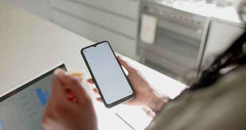 Woman Using Smartphone for Budget Management in Kitchen