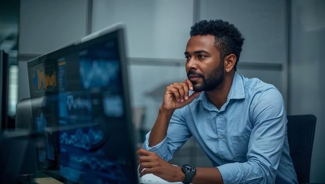 Focused analyst reviewing financial dashboards on multiple monitors in modern workspace