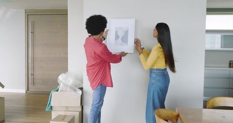 Couple hanging picture on wall during home renovation