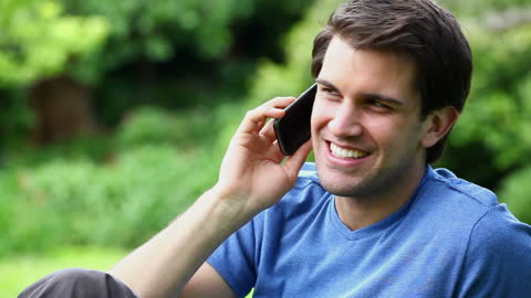 Cheerful Young Man Enjoying Phone Call in Park