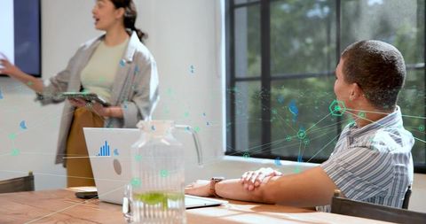 Female executive presenting strategy to team in modern conference room with laptop