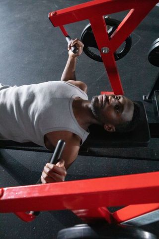 Focused Man Pushing Chest-Press Machine in Gym