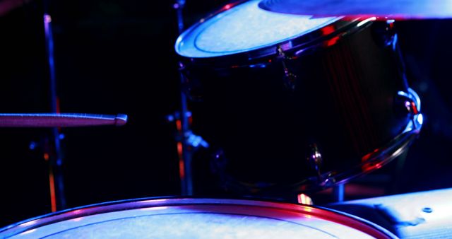 Close-up of a drum set on a stage, bathed in blue stage lighting, with copy space. The image captures the essence of a live music performance waiting to happen.