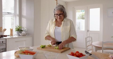 Senior woman preparing vegetables in bright home kitchen
