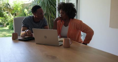African American Couple Engaged in Discussion with Laptop at Home