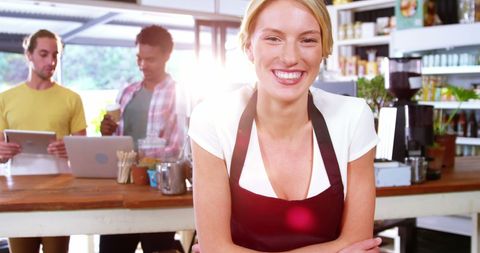 Professional waitress smiling behind cafe counter with colleagues