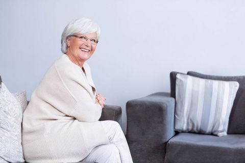 Elderly Woman Relaxes on Modern Sofa with Striped Cushions