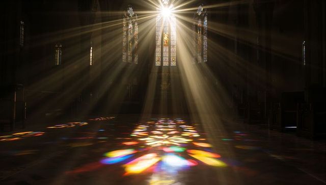 Sunlight streaming through stained glass in sacred church hall