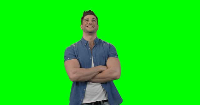 Man standing with arms crossed against green background