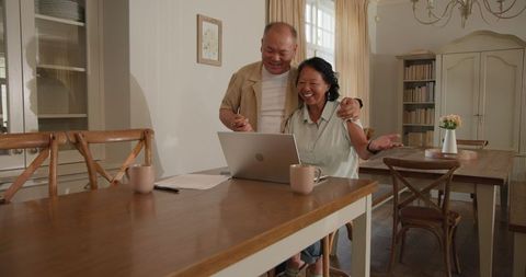 Happy senior couple using laptop for video call at home