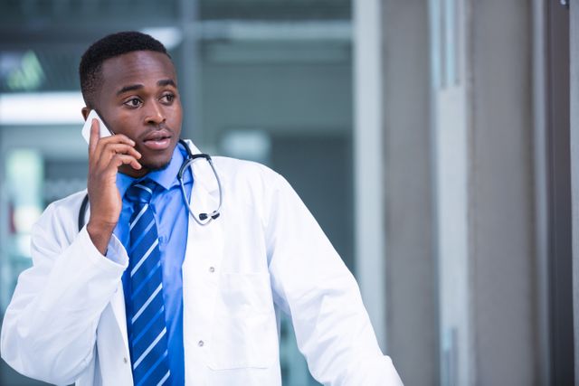 Tensed doctor talking on mobile phone in hospital