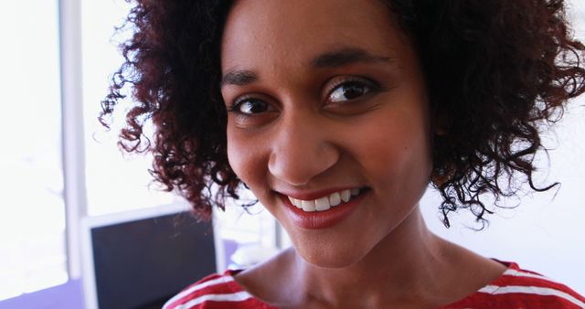 Smiling woman with curly hair in casual striped top indoors - Download Free Stock Images Pikwizard.com