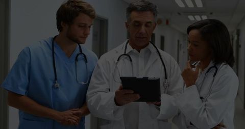 Medical Team Reviewing Patient Data on Tablet in Hospital Corridor