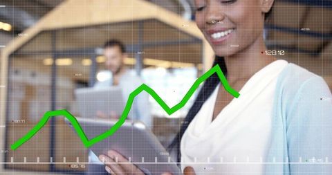 Smiling businesswoman using tablet with green growth chart overlay in modern coworking office