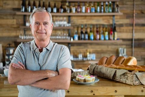 Senior baker proudly displaying baked goods in rustic bakery