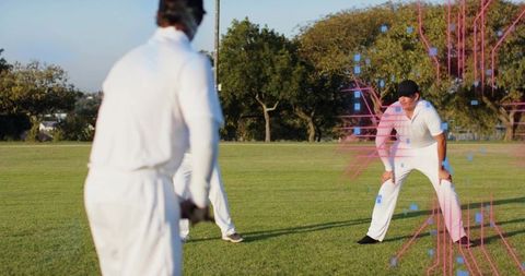 Crouching cricket fielder in black cap and whites facing batter with pink-blue digital overlay