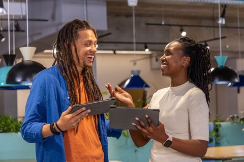 African American coworkers collaborating with tablets in modern coworking space