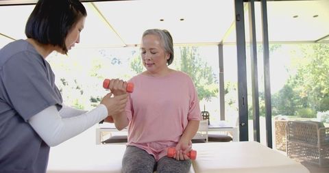 Senior Asian Woman Assisted in Physical Therapy Exercise at Home