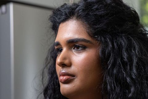 Indian woman gazing thoughtfully closeup with curly hair in modern kitchen
