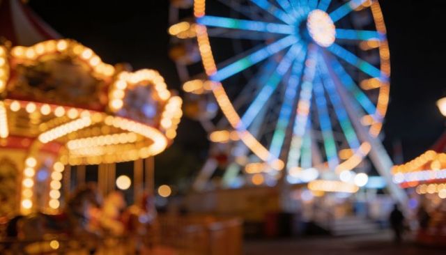 Glowing ferris wheel and carousel lights creating colorful nighttime fairground bokeh magic