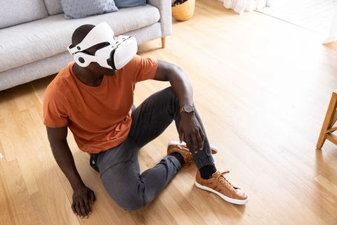 Man immersed in virtual reality sitting on living room floor