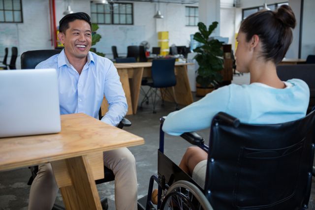 Smiling businessman interacting with disabled colleague in office