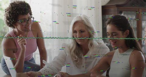 Multigenerational women collaborating over documents at dining table with laptop, daylight