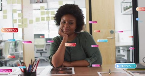 Sitting woman reviewing print proofs with tablet and augmented tags for creative review